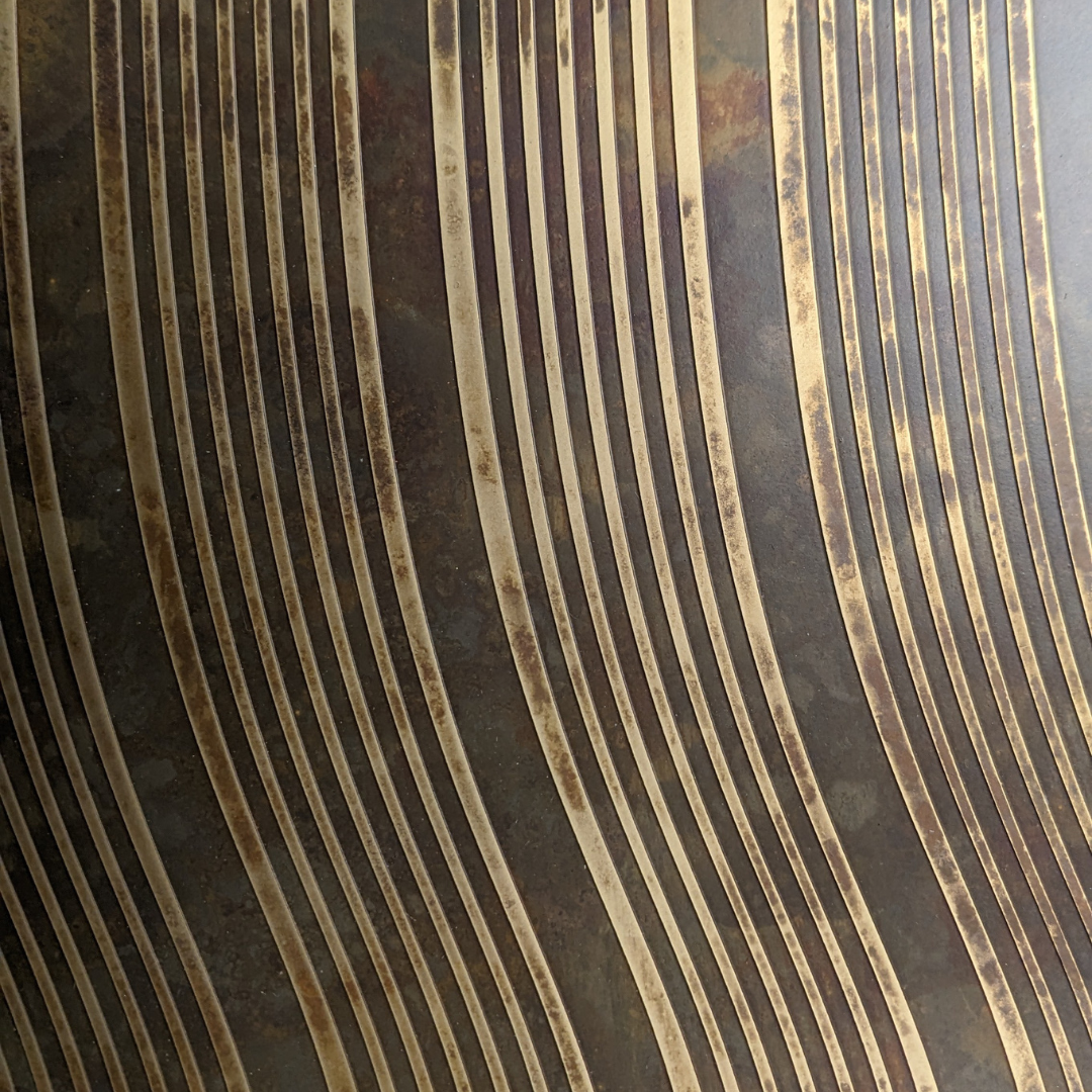 Curved etched linework with a hand-aged patina